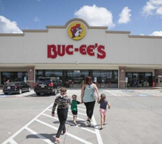 Picture of a family walking into the entrance of a Buc-ees store with the brand's name and logo present